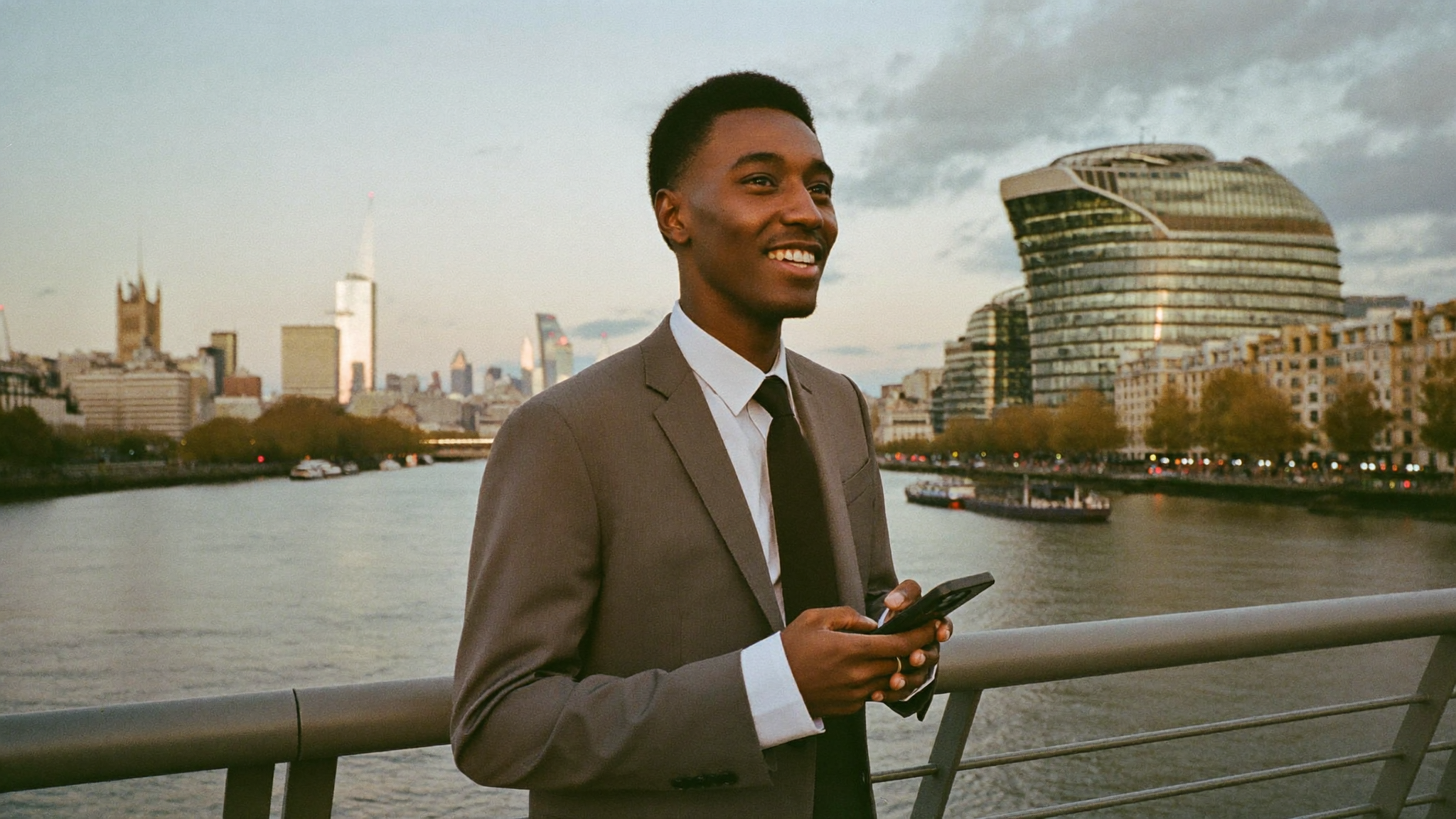 A young man in London using his phone by the river
